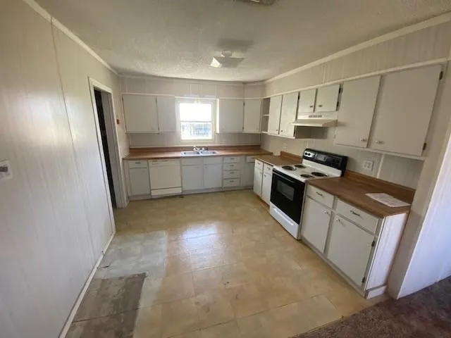 a large kitchen with a stove a sink dishwasher a refrigerator and white cabinets with wooden floor