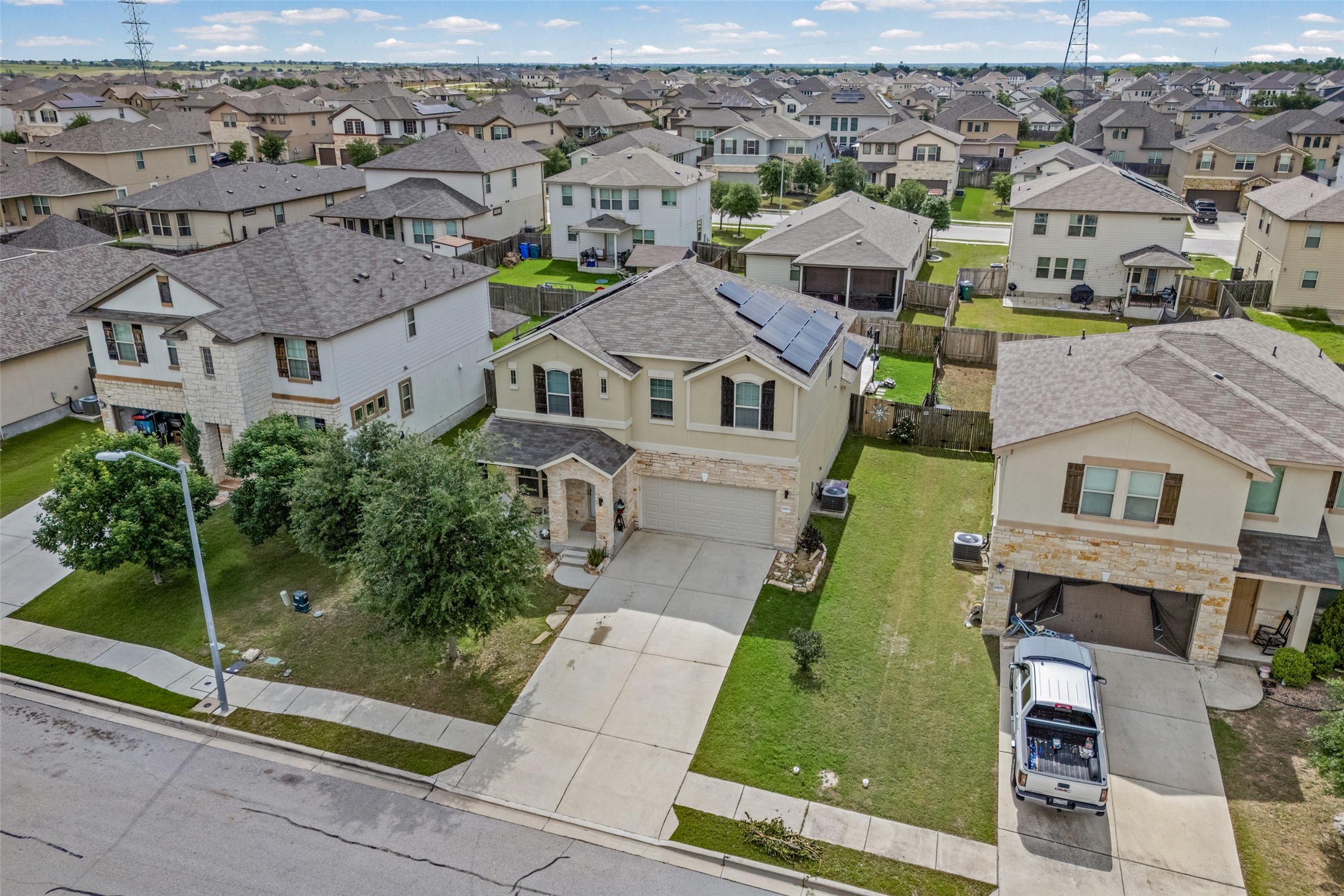 19113 Rookery Trail Pflugerville, TX 78660 - Photo 28 of 36 Two-story residence featuring a stone and stucco exterior, an attached two-car garage, solar panels, a paved driveway, and a fenced backyard
