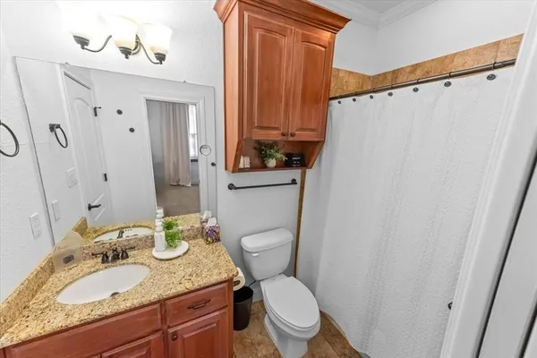 a bathroom with a granite countertop sink toilet and mirror