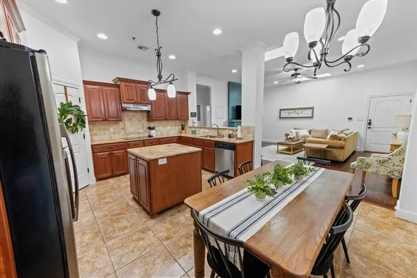 a kitchen with stainless steel appliances granite countertop a table chairs and a refrigerator