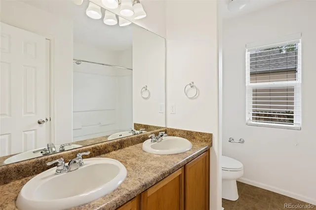 a bathroom with a granite countertop sink a toilet a mirror and a tub
