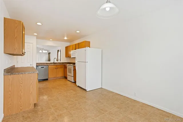 a view of kitchen with refrigerator and white cabinets