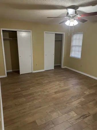a view of an empty room with window and chandelier fan