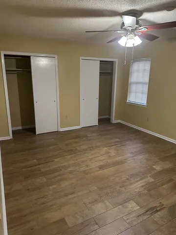 a view of an empty room with window and chandelier fan