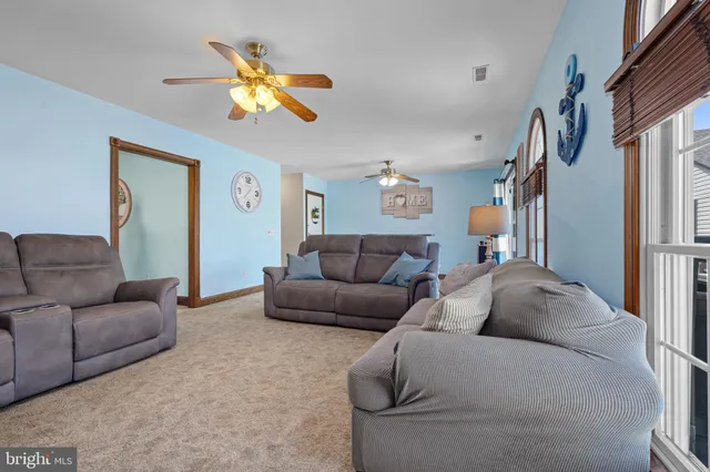 a living room with furniture a ceiling fan and a window