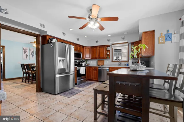 a kitchen with stainless steel appliances granite countertop a refrigerator a stove a sink a dining table and chairs with wooden floor