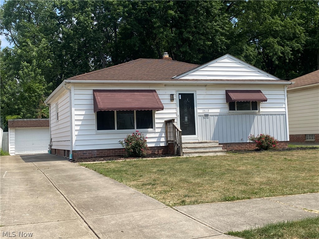 View of front facade with an outdoor structure, a garage, and a front lawn