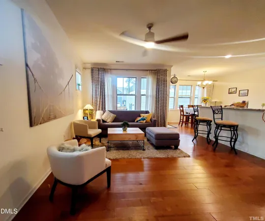 a living room with couches and kitchen view with wooden floor