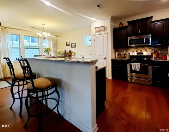 a kitchen with stainless steel appliances a dining table chairs microwave and sink