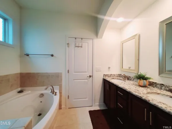 a bathroom with a granite countertop tub sink and mirror