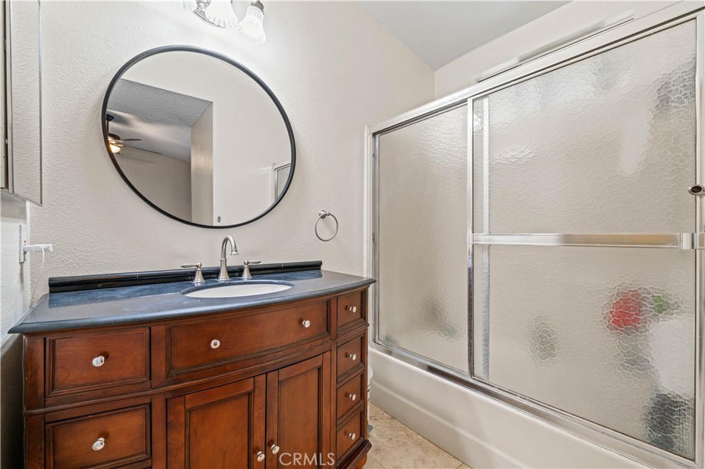 12052 Elk Boulevard Riverside, CA 92505 - Photo 13 of 25 a bathroom with a granite countertop sink a mirror and shower