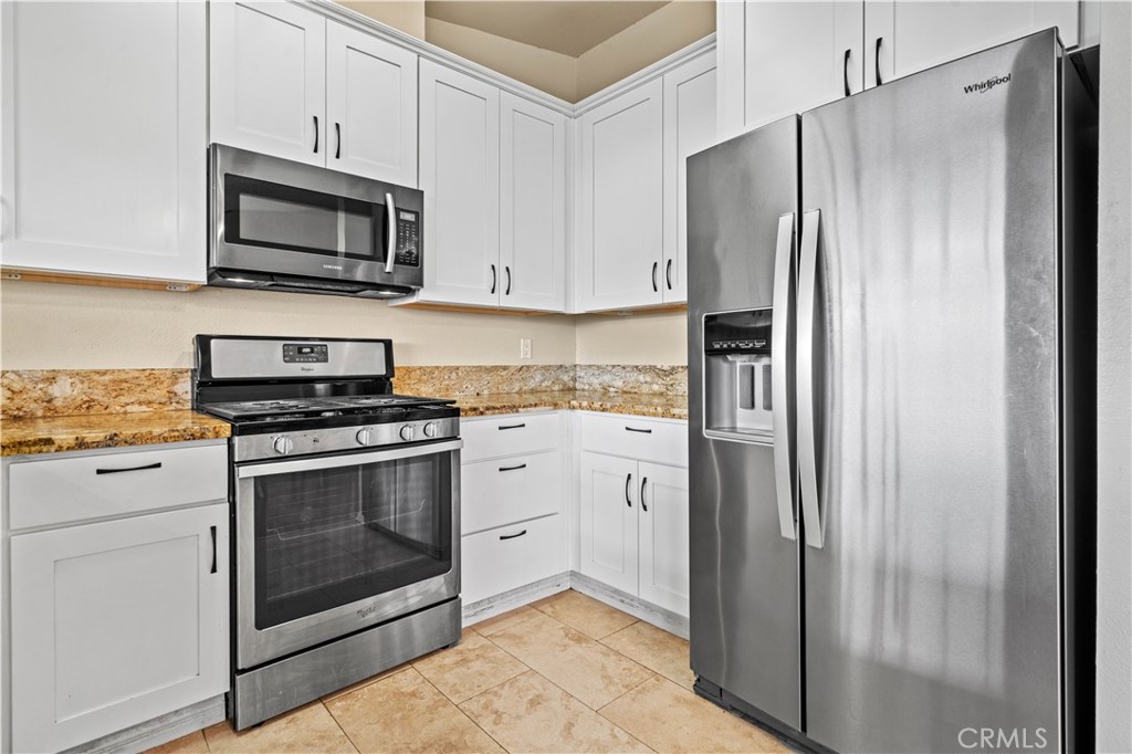 12052 Elk Boulevard Riverside, CA 92505 - Photo 9 of 25 a kitchen with stainless steel appliances white cabinets a stove and a refrigerator