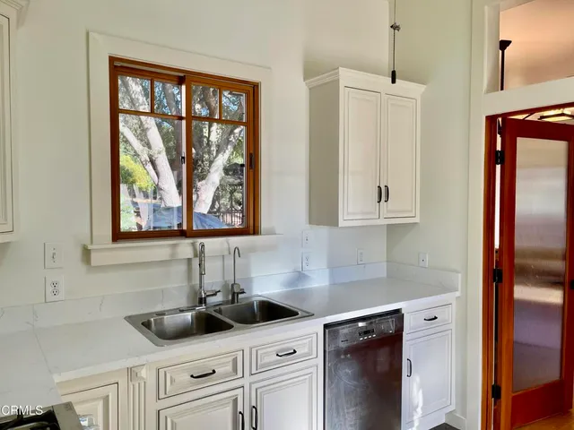a kitchen with stainless steel appliances white cabinets and a window