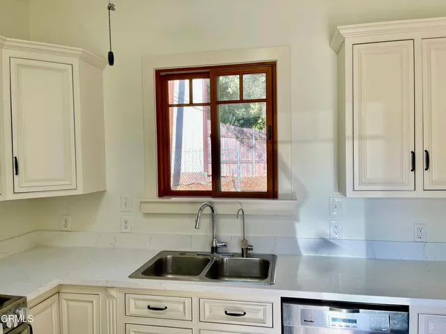 a kitchen with stainless steel appliances granite countertop white cabinets and a window