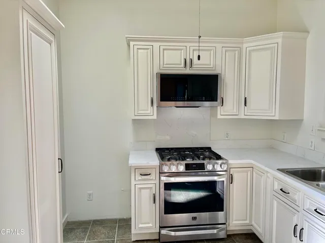 a kitchen with stainless steel appliances granite countertop white cabinets a microwave oven and a sink with granite countertops