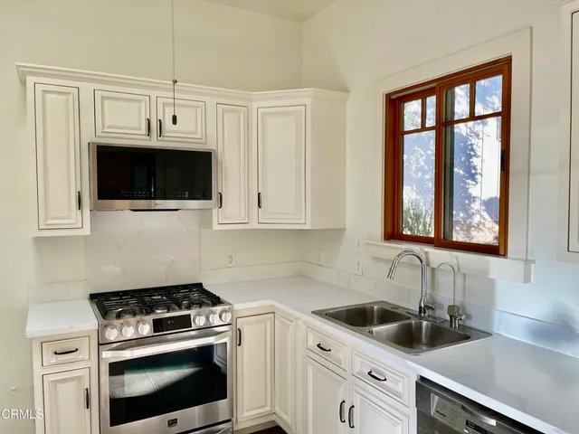a kitchen with cabinets stainless steel appliances a sink and a window