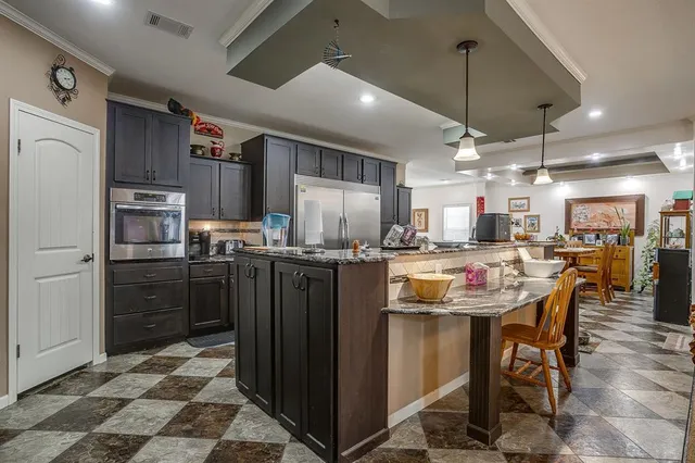a kitchen with kitchen island a counter top space a refrigerator and cabinets