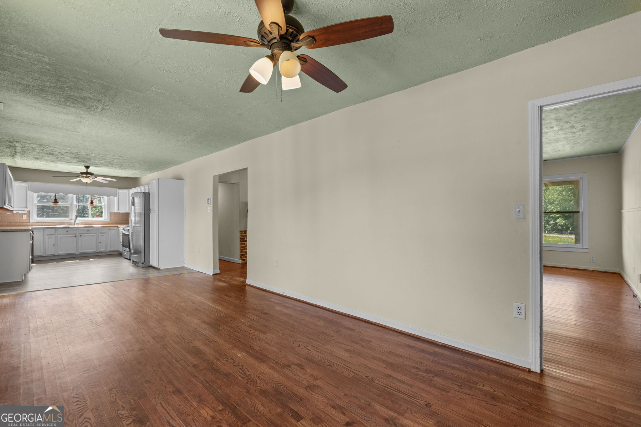 49 Frost Road Bowdon, GA 30108 - Photo 17 of 60 an empty room with wooden floor chandelier fan and windows