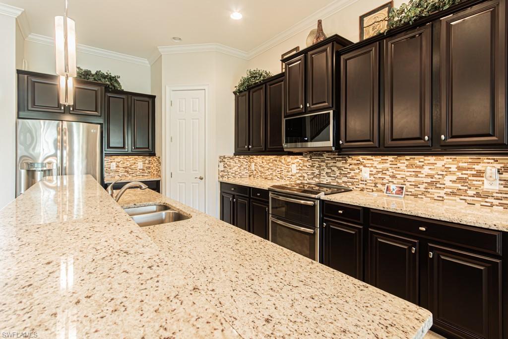 7761 Bucks Run Drive Naples, FL 34120 - Photo 13 of 50 a kitchen with kitchen island granite countertop wooden cabinets a refrigerator and a sink