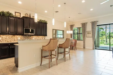 a open kitchen with stainless steel appliances granite countertop a stove a refrigerator a kitchen island a couches and chairs with wooden floor