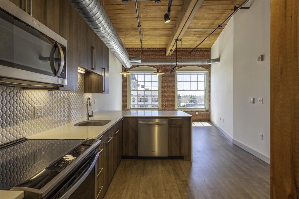 165 Thorndike Street, Unit 403 Lowell, MA 01852 - Photo 2 of 10 a kitchen with stainless steel appliances granite countertop a sink stove and wooden floor