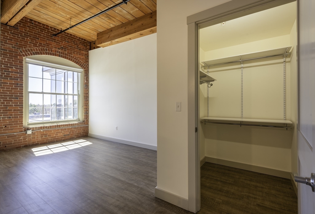 165 Thorndike Street, Unit 403 Lowell, MA 01852 - Photo 4 of 10 an empty room with wooden floor door and windows