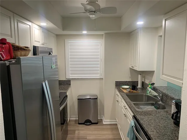 a kitchen with stainless steel appliances granite countertop a sink a stove a refrigerator a washer dryer and cabinets