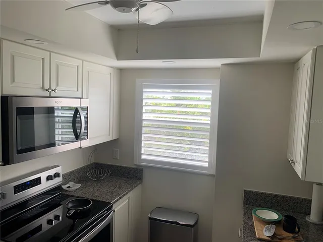 a kitchen with granite countertop a stove a sink and a microwave