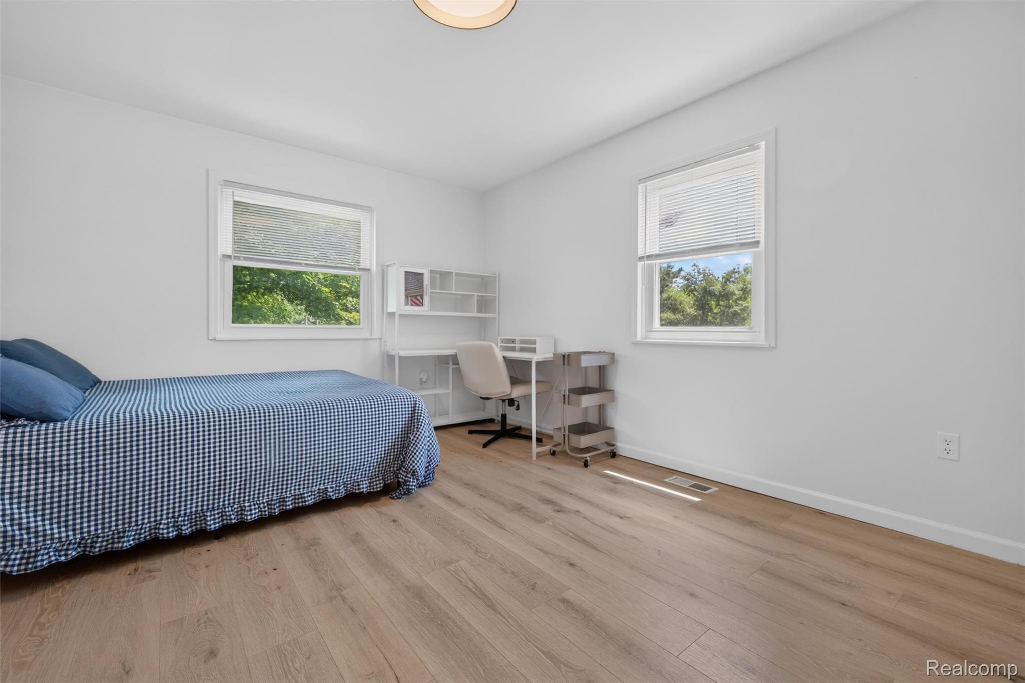 5244 Oleksyn Road Flint, MI 48504 - Photo 11 of 70 Bright room featuring two large windows with white trim, wood-finish flooring, and a contemporary ceiling light fixture