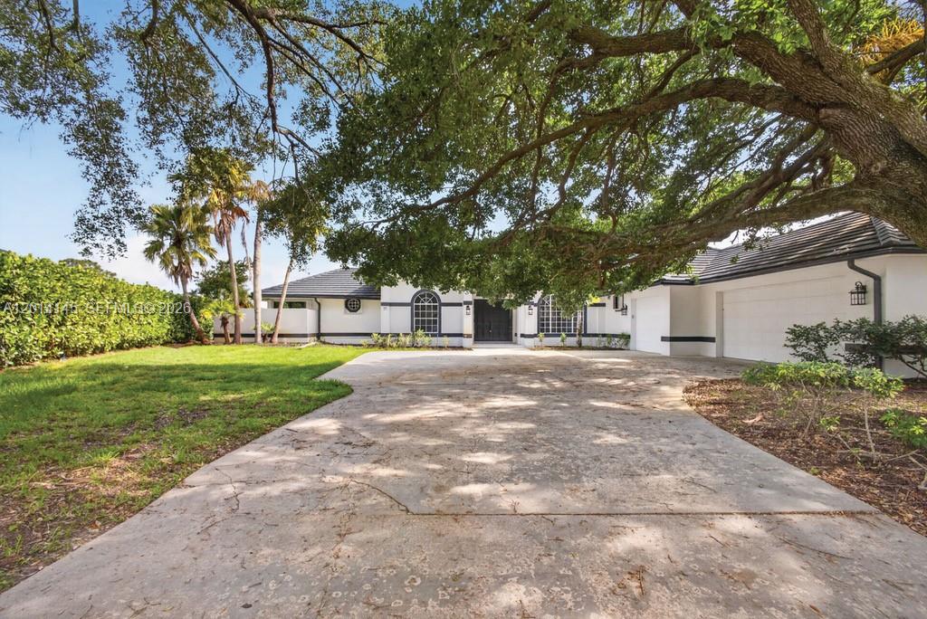 19558 Red Gum Trail Jupiter, FL 33458 - Photo 1 of 81 a view of a white house with a big yard and large trees