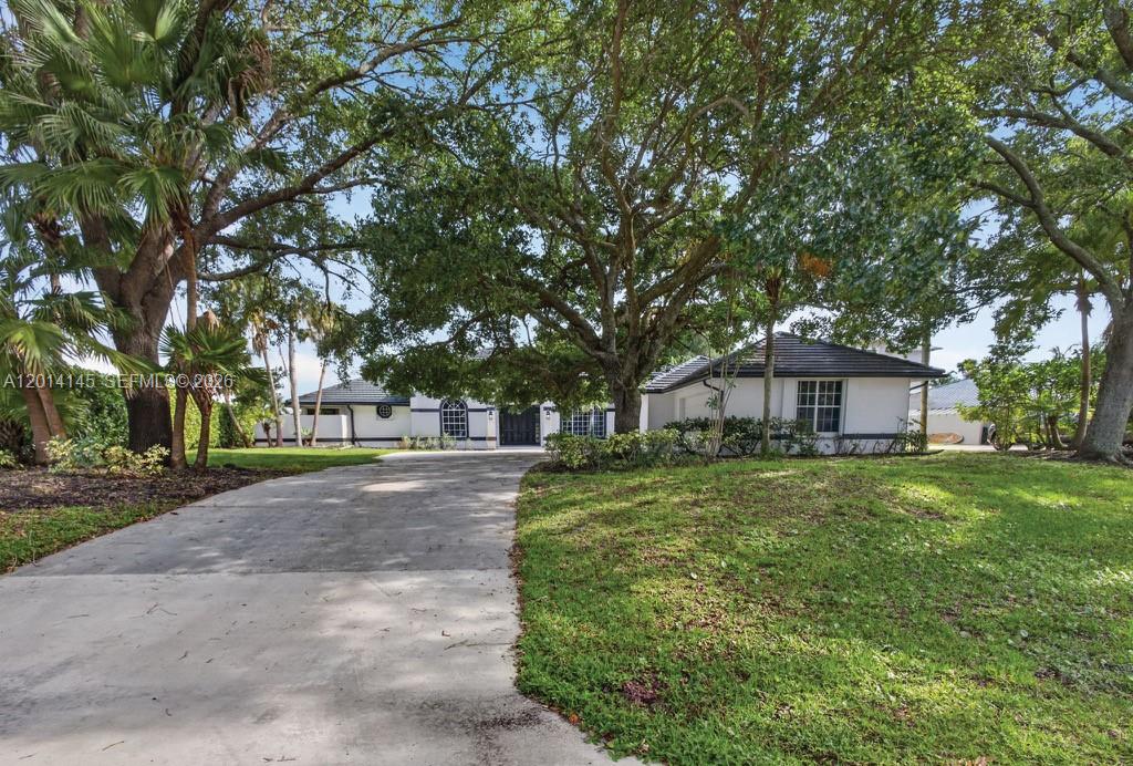19558 Red Gum Trail Jupiter, FL 33458 - Photo 2 of 81 a view of a yard in front of a house with large trees