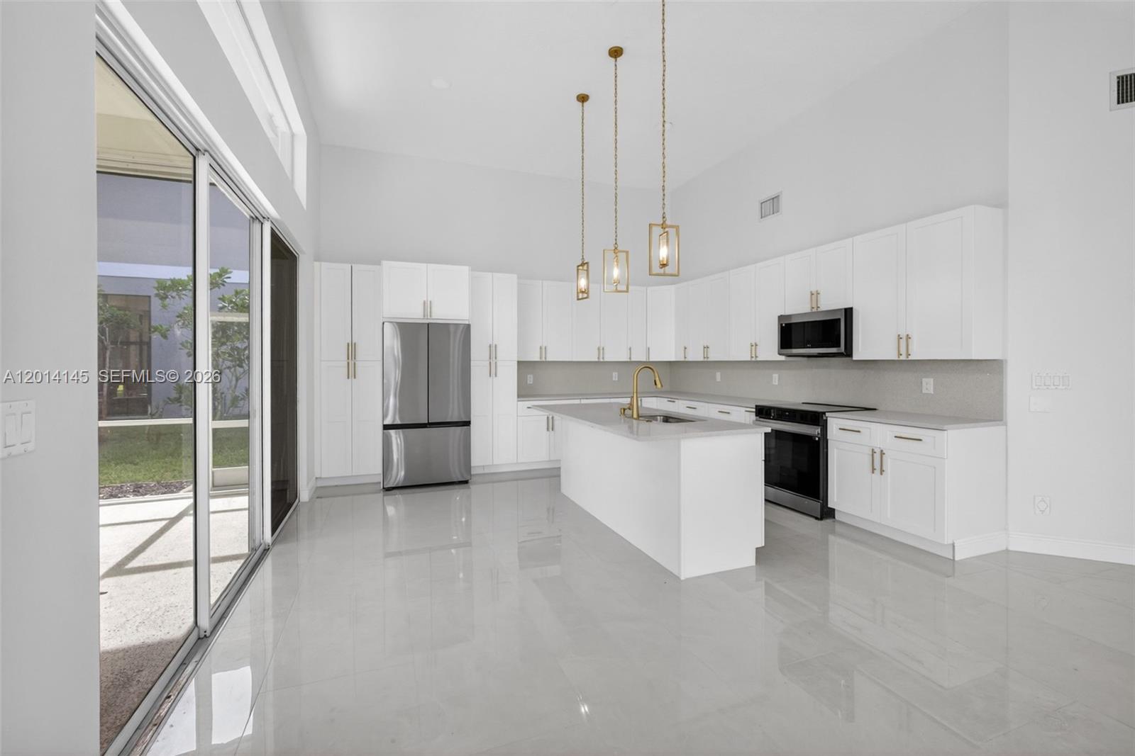 19558 Red Gum Trail Jupiter, FL 33458 - Photo 23 of 81 a large kitchen with stainless steel appliances kitchen island granite countertop a stove a sink and white cabinets