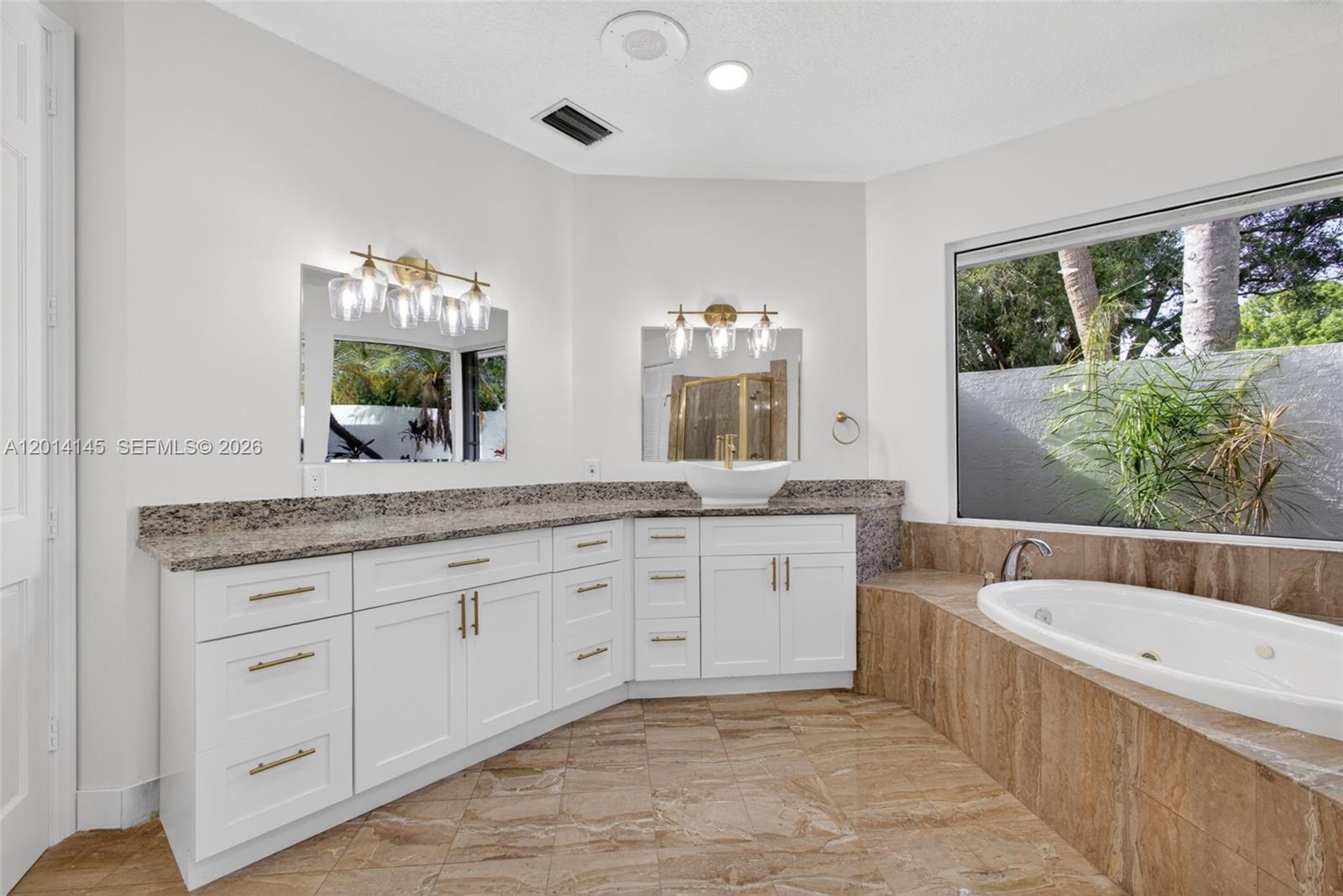 19558 Red Gum Trail Jupiter, FL 33458 - Photo 41 of 81 a bathroom with a granite countertop tub sink and mirror
