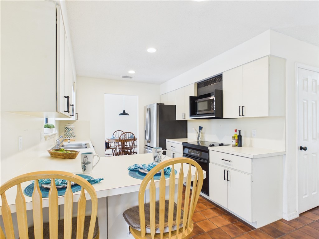 225 Midvale Terrace Sebastian, FL 32958 - Photo 12 of 25 a kitchen with stainless steel appliances granite countertop a stove a sink a microwave a dining table and chairs