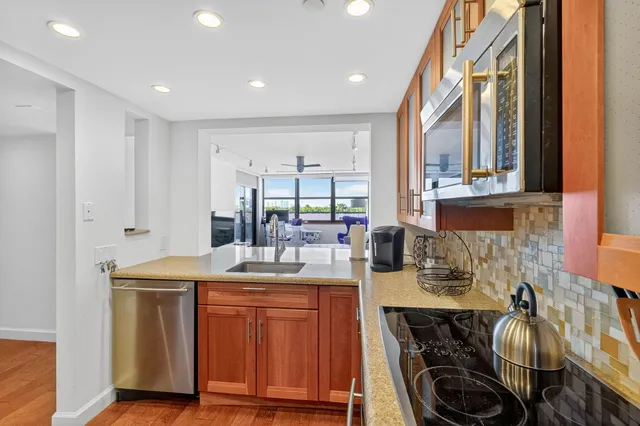 a kitchen with stainless steel appliances granite countertop a refrigerator a stove and a sink with wooden floor