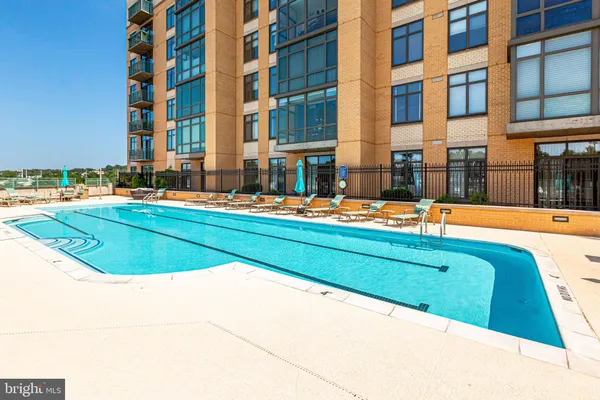 a view of building with large pool and outdoor seating