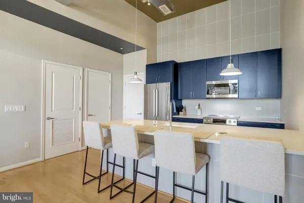 a kitchen with stainless steel appliances a table chairs refrigerator and cabinets