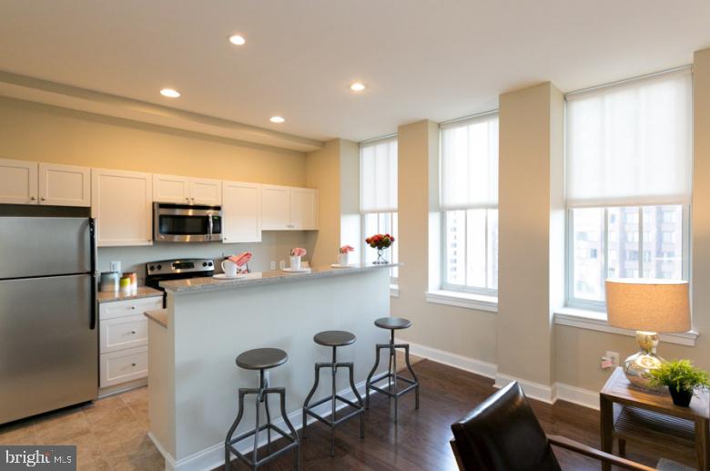 301 North Charles Street, Unit 2BR Baltimore, MD 21202 - Photo 47 of 48 a kitchen with stainless steel appliances a dining table chairs refrigerator and sink