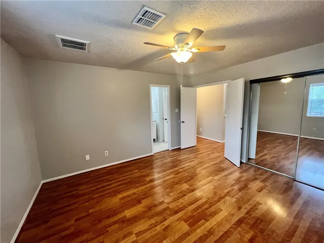 a view of an empty room with wooden floor and a chandelier fan