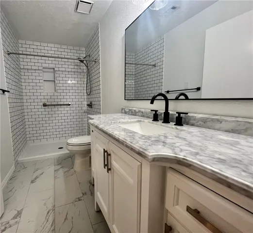 a bathroom with a granite countertop sink a toilet and mirror