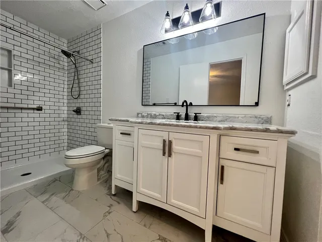 a bathroom with a granite countertop toilet sink and mirror