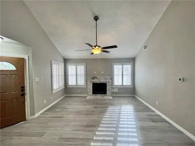 a view of a livingroom with wooden floor a ceiling fan and windows
