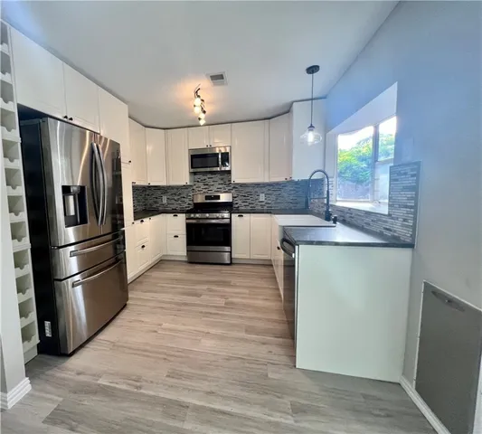 a kitchen with stainless steel appliances granite countertop a refrigerator a stove top oven a sink and dishwasher