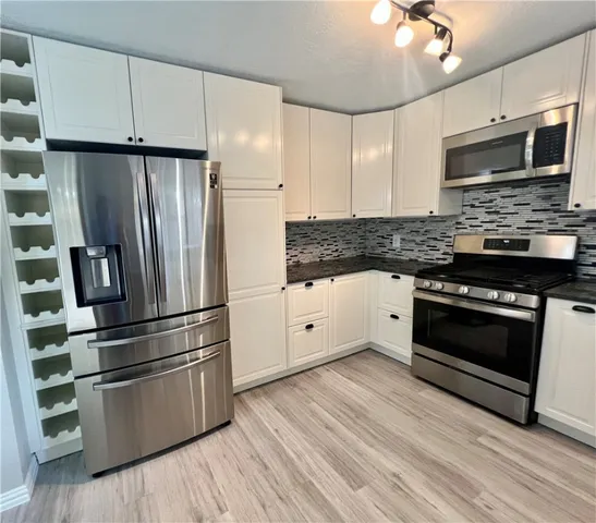 a kitchen with granite countertop a refrigerator stove and kitchen island
