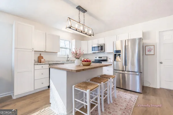 a kitchen with stainless steel appliances a refrigerator a stove a sink and white cabinets