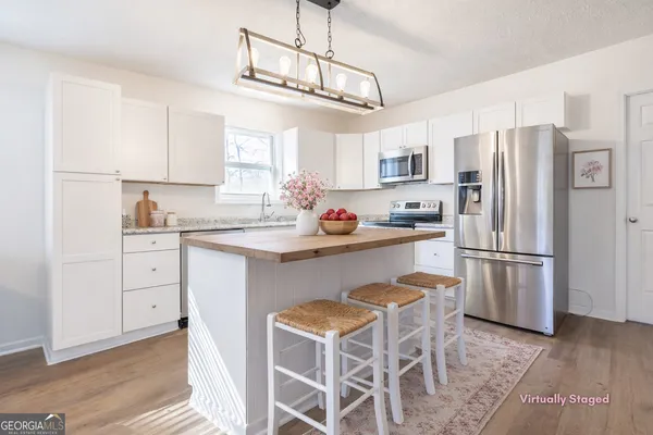 a kitchen with stainless steel appliances a refrigerator a stove a sink and white cabinets