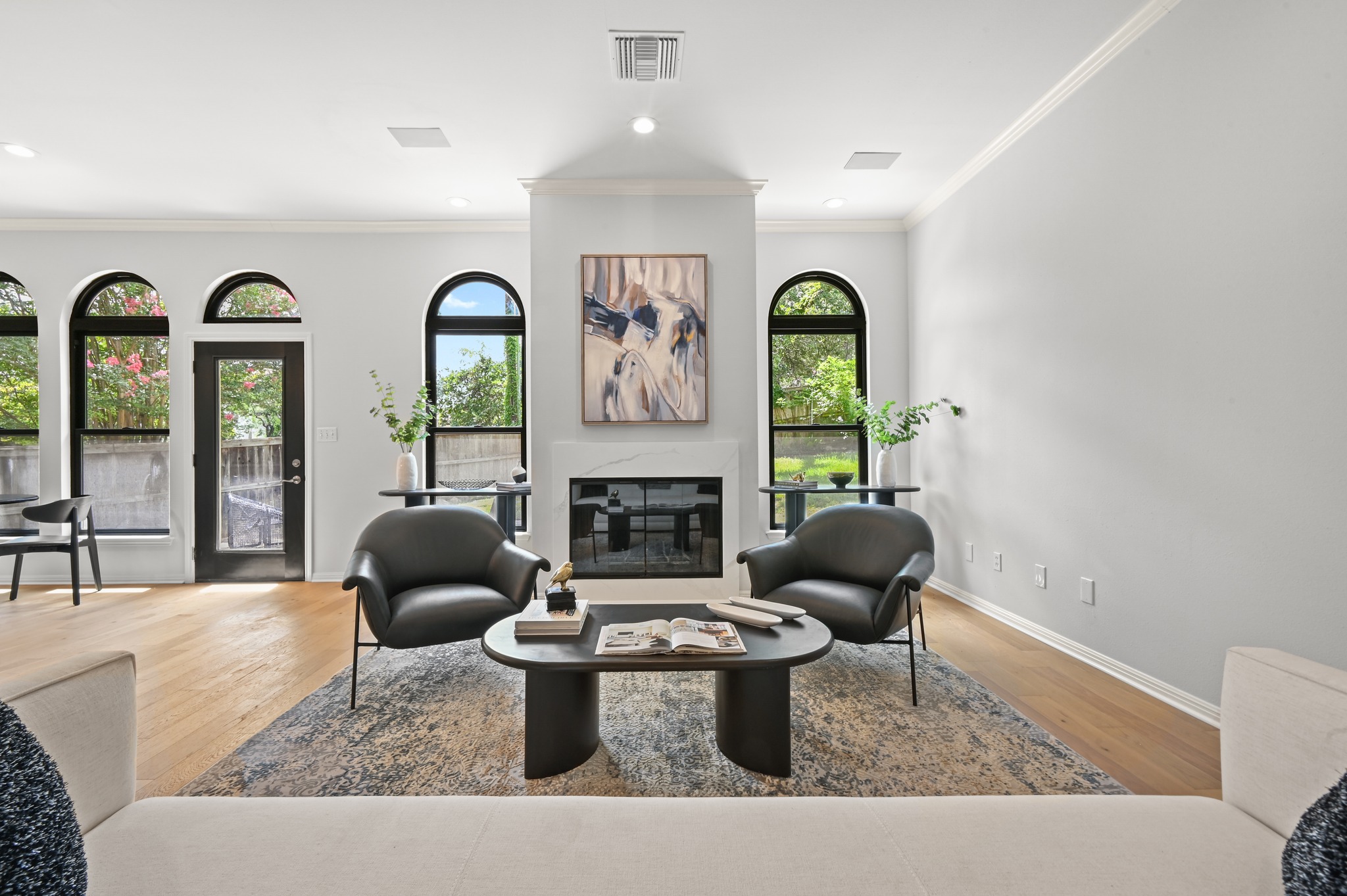 1107 Bowie Road Austin, TX 78733 - Photo 10 of 40 Arched windows frame verdant views in this naturally illuminated living area, featuring a stately fireplace.