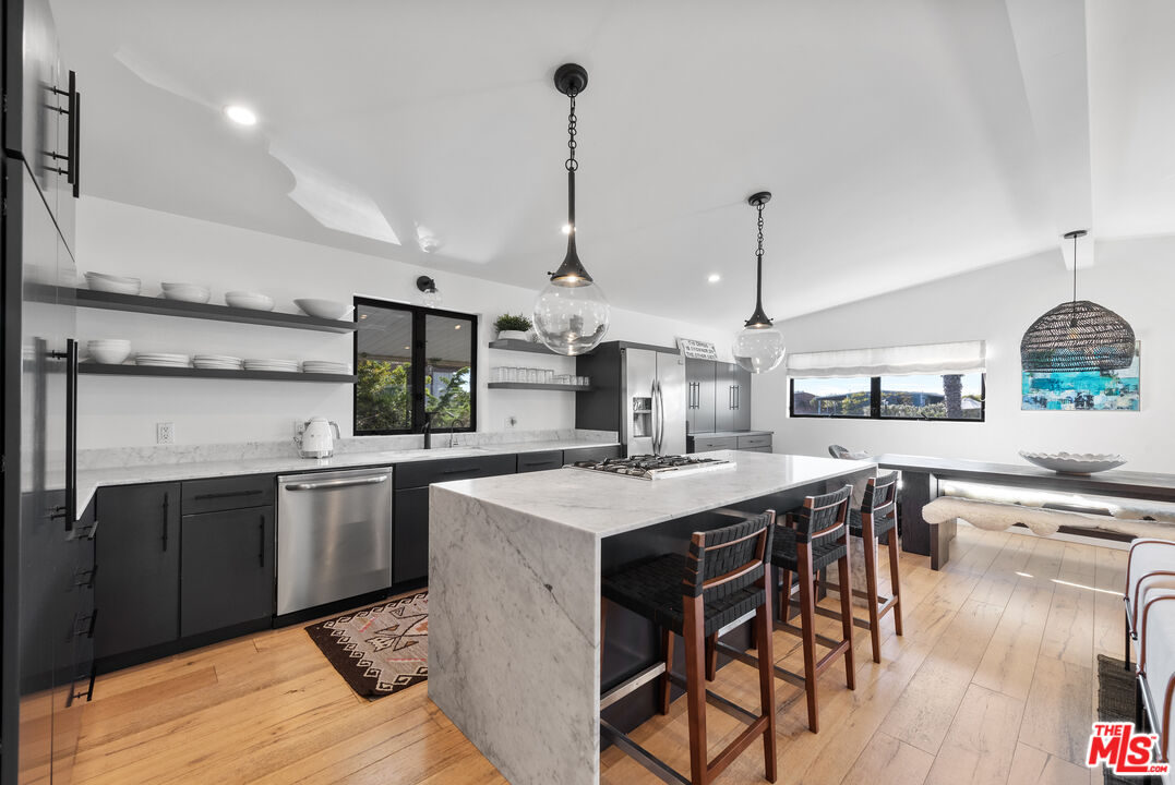 29500 Heathercliff Road, Unit 14 Malibu, CA 90265 - Photo 8 of 28 a kitchen with stainless steel appliances granite countertop a sink a stove and chairs