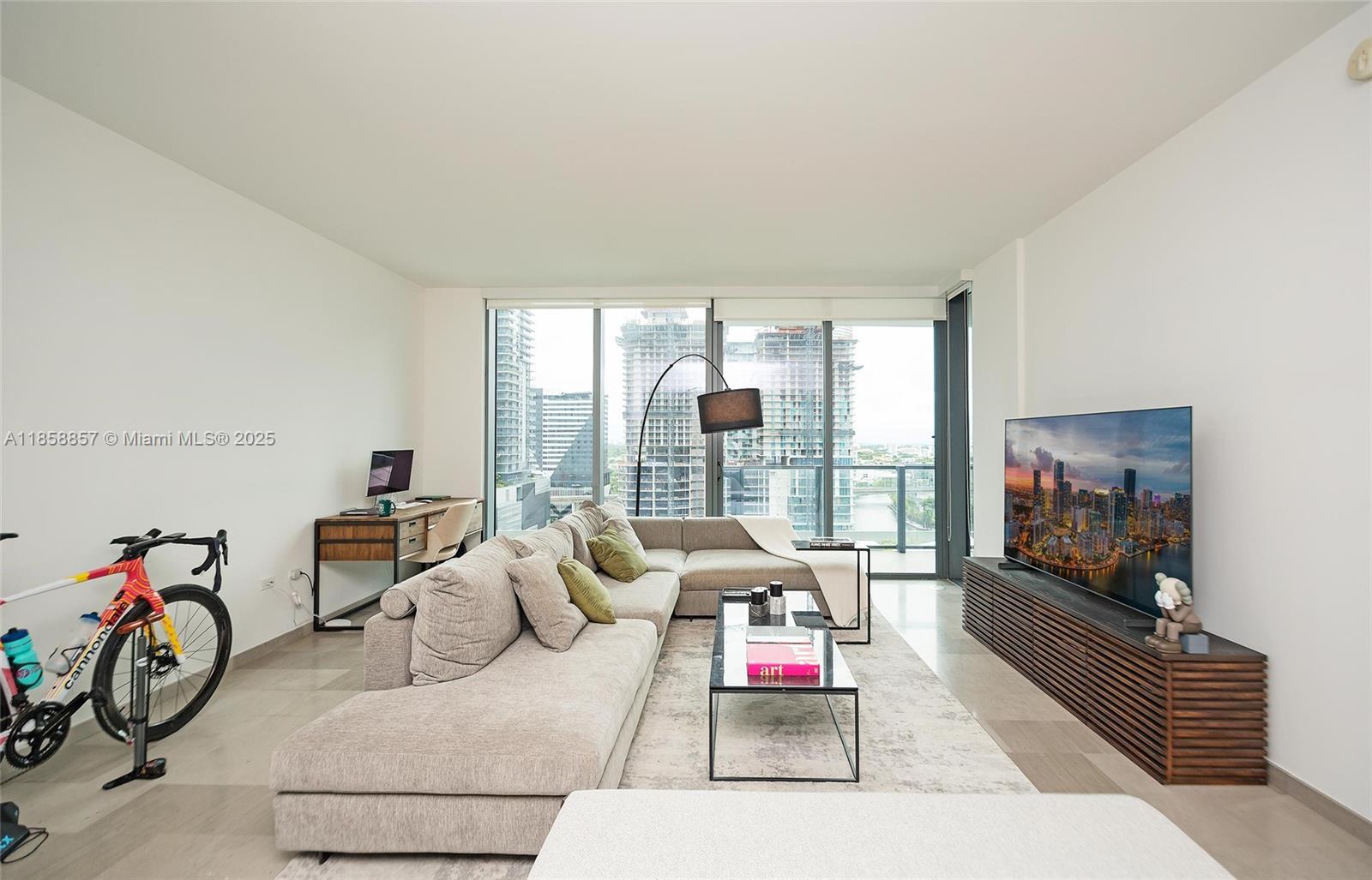 68 Southeast 6th Street, Unit 1008 Miami, FL 33131 - Photo 13 of 37 a living room with furniture and a flat screen tv