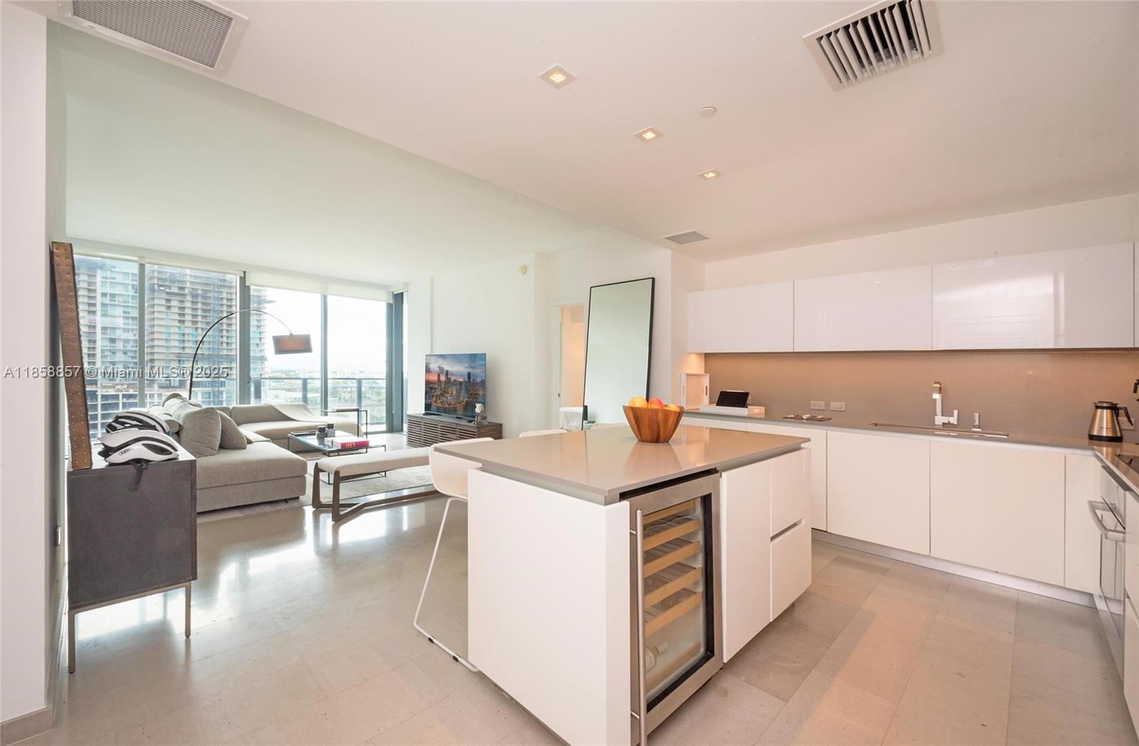 68 Southeast 6th Street, Unit 1008 Miami, FL 33131 - Photo 3 of 37 a view of a kitchen counter top space with granite countertop a living room and white cabinets